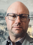 Click here to learn more about Greg. Greg Riddick headshot.